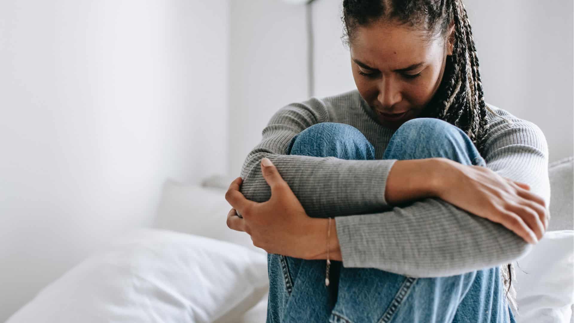 Photo Of Upset Woman Embracing Knees On Bed is one of the symptoms of addiction