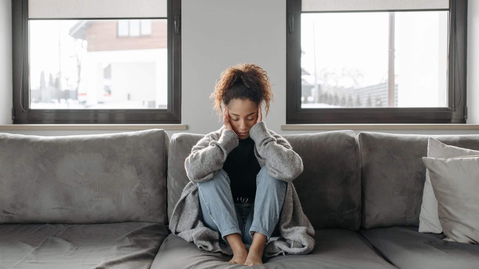 Woman Sitting On A Sofa Experiencing Headache