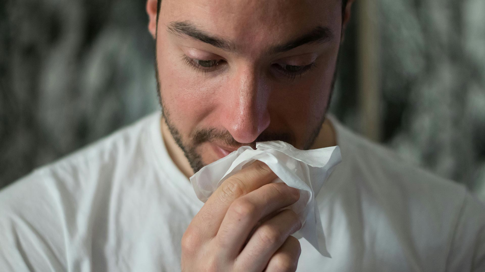 man wiping nose with tissue paper