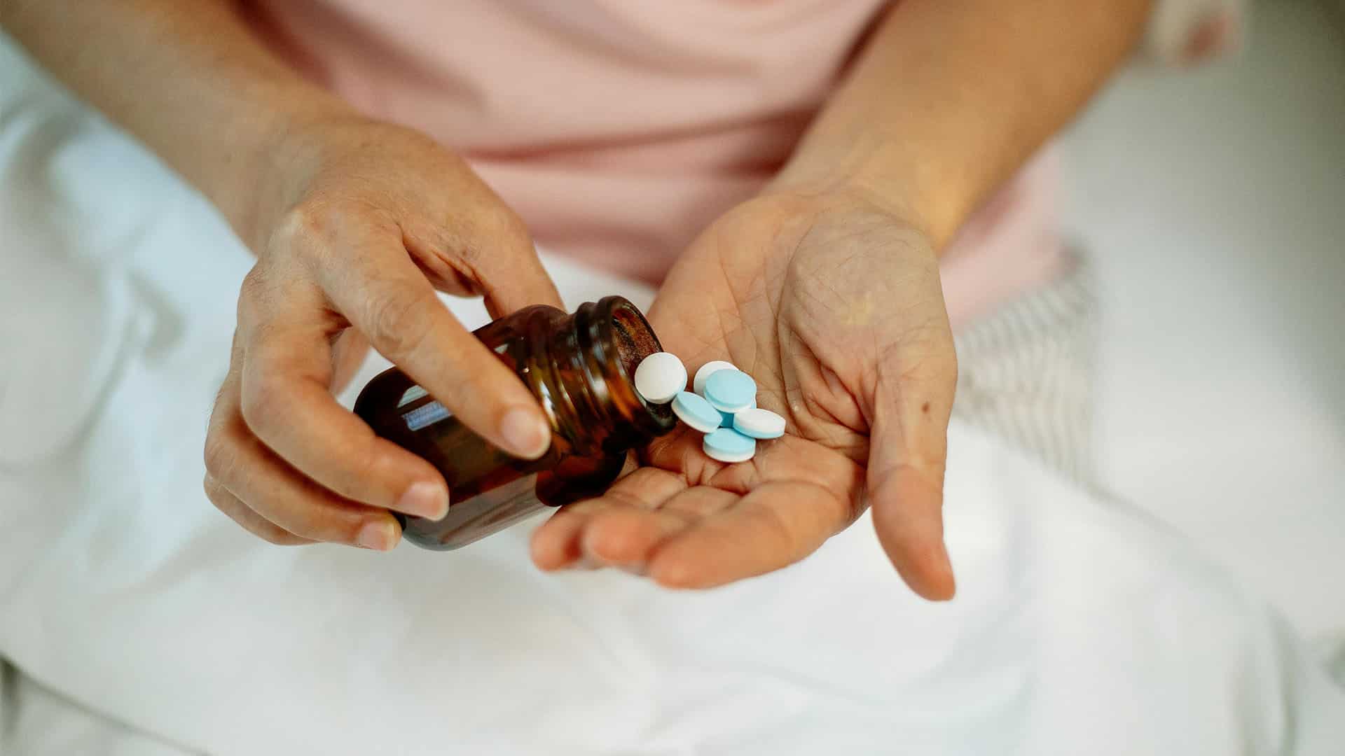 woman taking pills from jar on hand