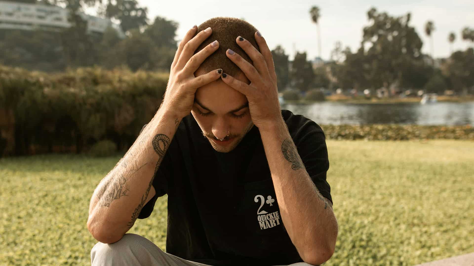 man holding his head sitting outside