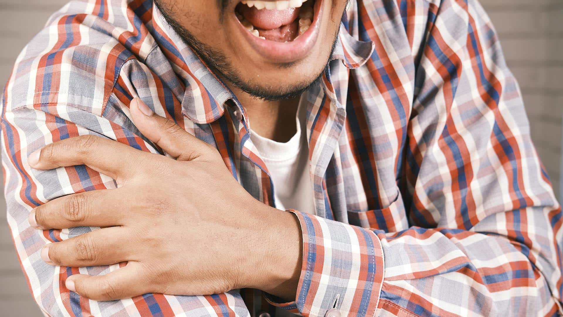 Close-up Photo of an aching Man holding his Shoulder