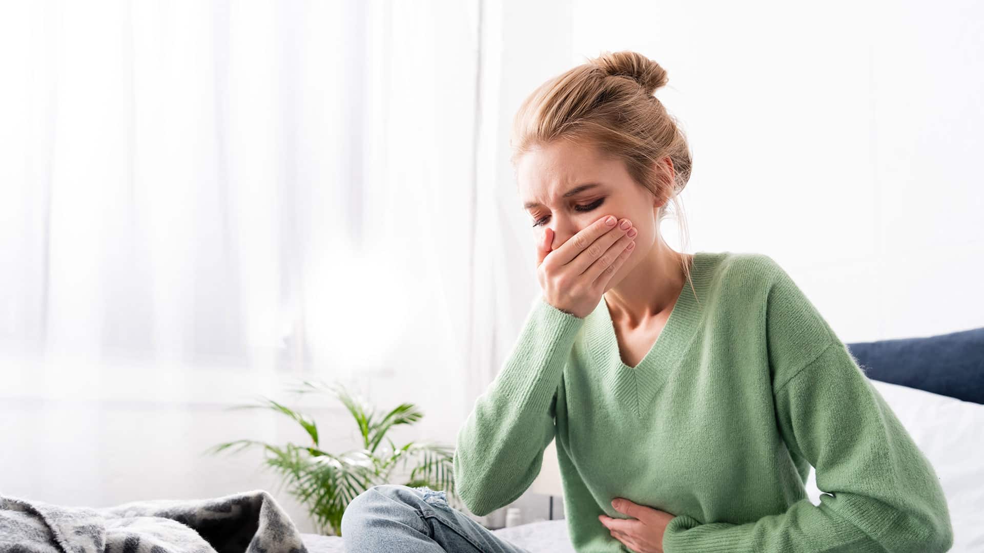 woman having nausea sitting bed