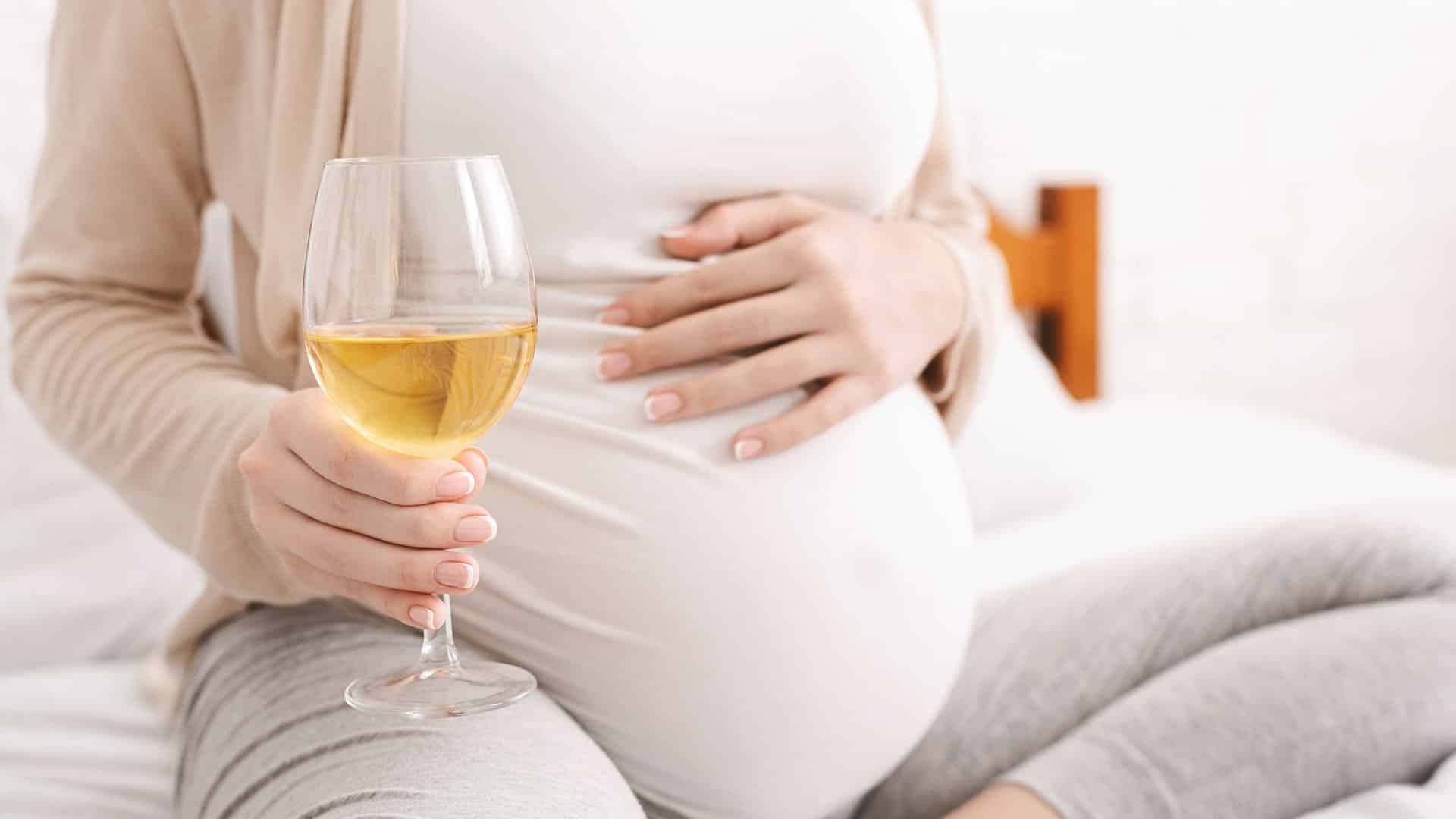 pregnant woman holding glass of white wine